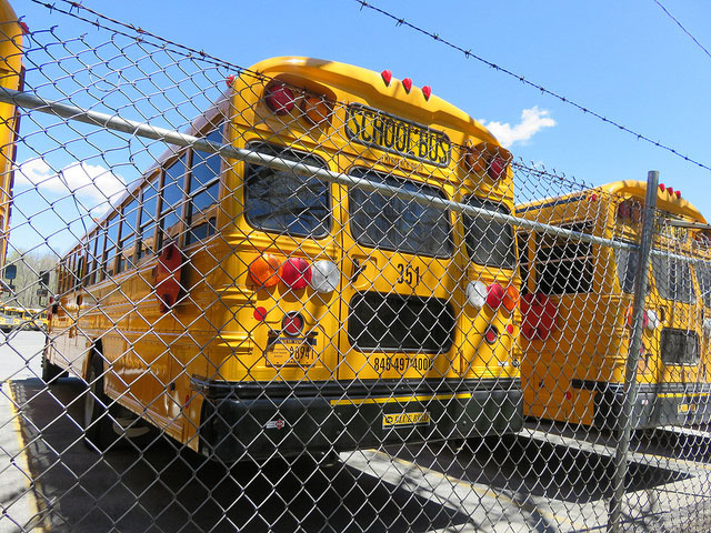 A yellow school bus in a bus yard
